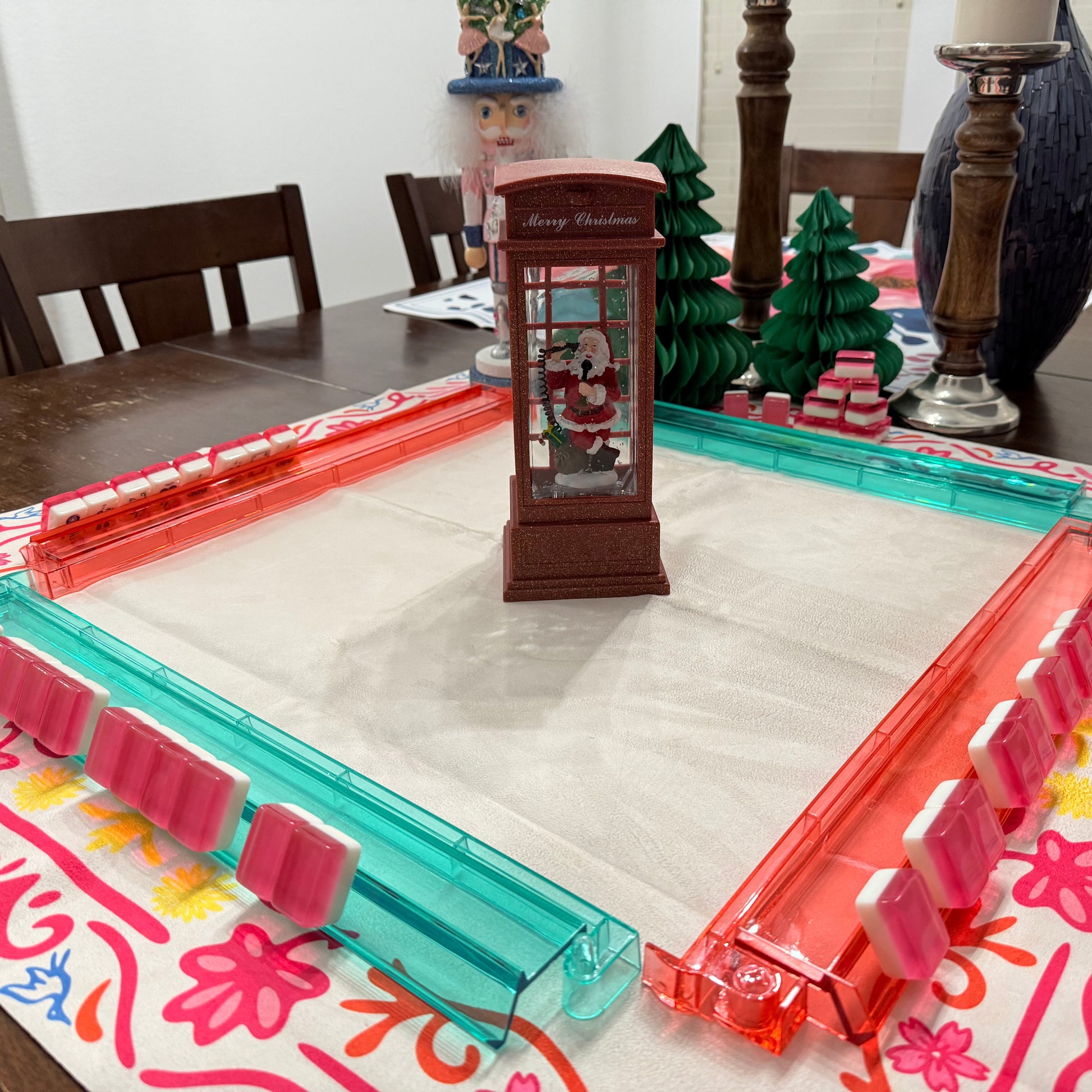 Decorative table setting with a colorful placemat, red and pink floral design, and a small clock.